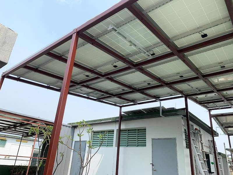 The canopy from below at the side, with a frangipani tree in the foreground - Rooftop steel canopy carrying solar panels (M28) | Wong Lye, BCA General Builder Class 2, Singapore