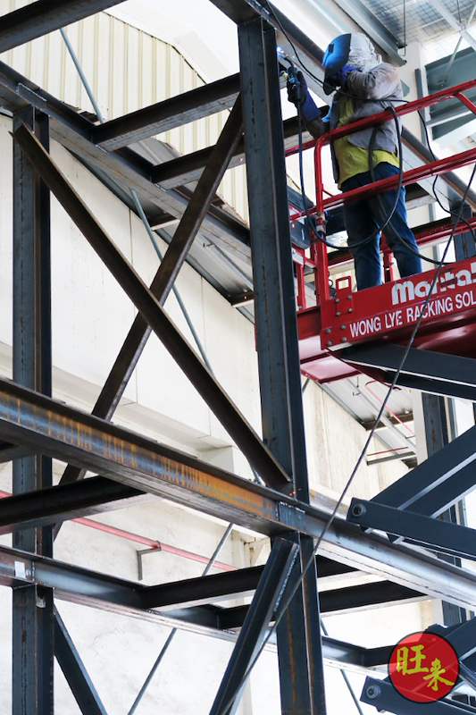 Welder on a boom lift welding the steel racking frame at height - Heavy-duty cable drum racking in a cable yard (TSE) | Wong Lye, BCA General Builder Class 2, Singapore