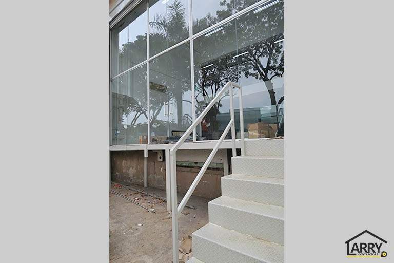 Steel entrance staircase with checker-plate treads and a pipe handrail beside the glass wall - Framed glass frontage and steel entrance stair for an industrial unit (M09) | Wong Lye, BCA General Builder Class 2, Singapore