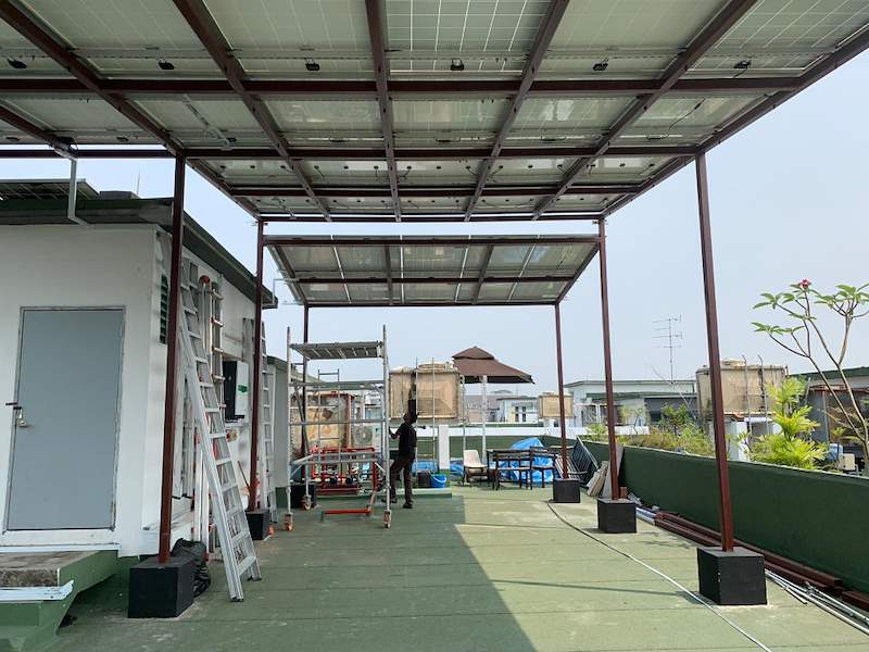Under the canopy - the terrace with a scaffold and ladder, neighbouring buildings beyond - Rooftop steel canopy carrying solar panels (M28) | Wong Lye, BCA General Builder Class 2, Singapore