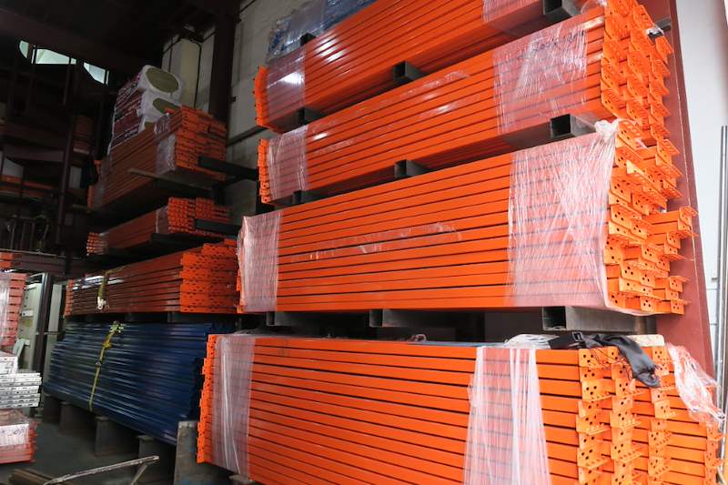Shrink-wrapped bundles of orange racking beams stacked on blue frames - Pallet racking beams and frames stacked in a warehouse (M12) | Wong Lye, BCA General Builder Class 2, Singapore