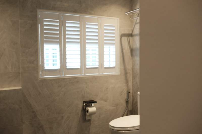 Bathroom with beige stone-look wall tiles and a window fitted with white plantation shutters - Terrace house A&A with new facade and full interior (3TBA) | Wong Lye, BCA General Builder Class 2, Singapore