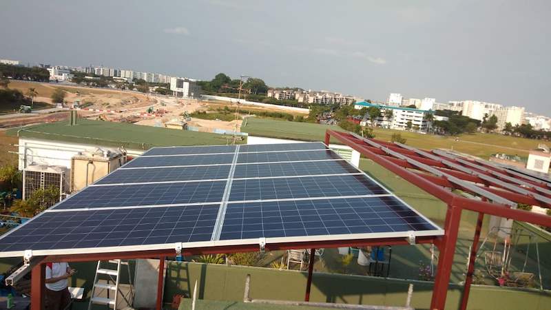 Solar panels on a tilted frame at the roof edge, looking out over open land - Rooftop steel canopy carrying solar panels (M28) | Wong Lye, BCA General Builder Class 2, Singapore